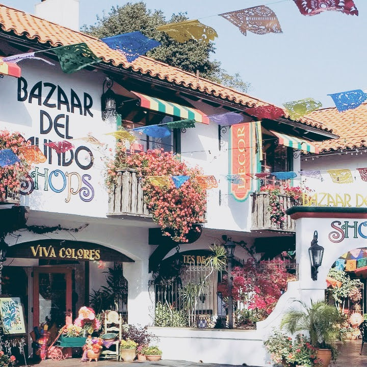 Bazaar Del Mundo storefront. It is a white Mexican style house with bright colorful bougainvilleas. One of the stores that carries Swil Arts prints